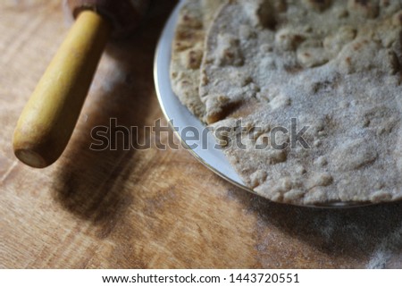 Traditional Indian Chapati Bread on a white plate and wooden table. some flour on the table