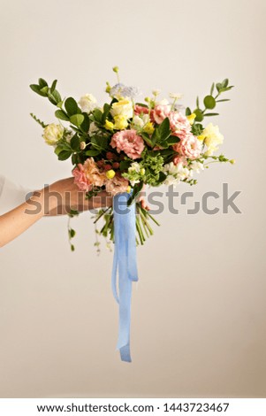 Girl's hands holding beautiful wedding flowers bouquet on white