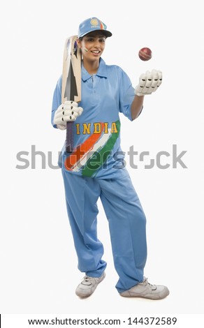 Portrait of a female cricketer tossing a cricket ball and smiling