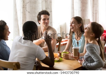 Mixed race happy young people gathering in cafe, sitting at table, chatting, talking, drinking coffee, spending funny time, diverse millennial guys and girls, students or best friends meeting. Royalty-Free Stock Photo #1443730790