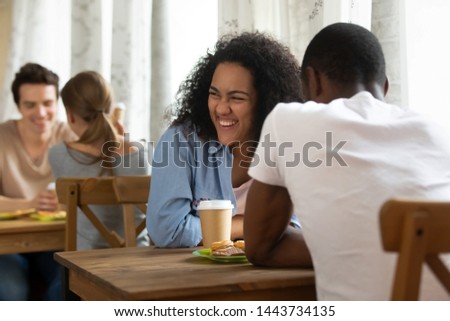 Happy young mixed race girl attending speed dating, getting acquainted with interesting people, joking, laughing, having fun. Millennial woman meeting black friend, enjoying spending time together. Royalty-Free Stock Photo #1443734135
