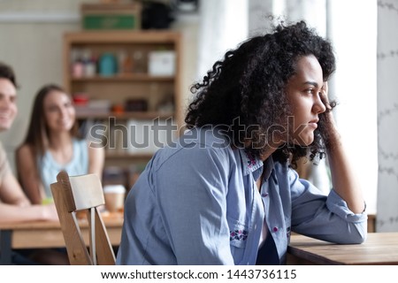 Young thoughtful upset depressed mixed race girl sitting alone near window in cafe, suffering from racial discrimination, bullying or gossips, feeling low self-esteem, rejected by caucasian people. Royalty-Free Stock Photo #1443736115