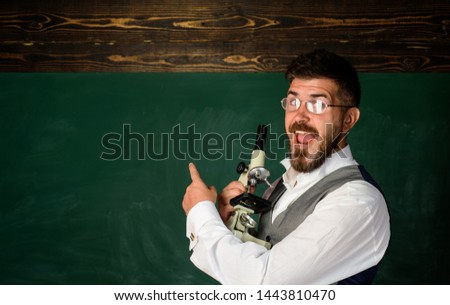 Confident male teacher in classroom. Teacher in classroom at elementary school. Teacher giving lesson to students. Education, high school and people concept - happy teacher over blackboard background.