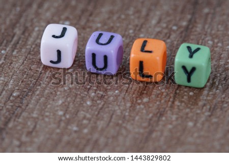 July wording from alphabet beads on a wooden surface. selective focus 