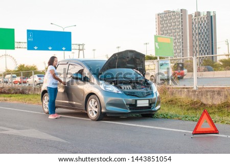 Asian teenage women holding a mobile phone Walking around the car, stressful mood during the evening hours. Along the highway Because her car broke down And she is waiting for help from someone.