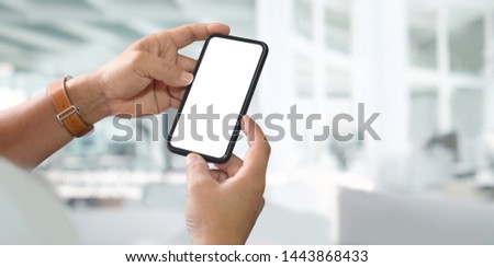 Man hands holding blank screen smartphone with blurred background.	