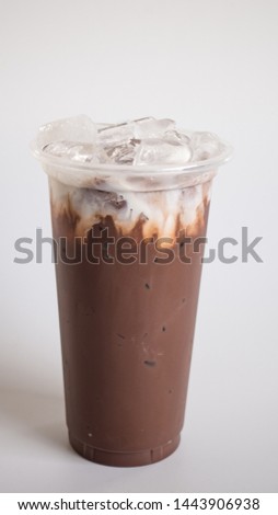 Iced cocoa in takeaway cup and milk foam isolated on white background, macro.