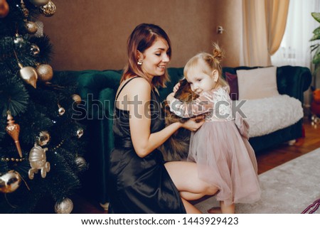 Elegant mother in a black dress. Family with cristmas gifts. Cute little girl