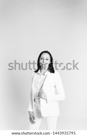 Studio portrait of an attractive young woman in a white suit against a plain background