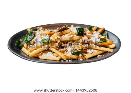 Isolated close-up French fries with fried basil, Thai chili and feta cheese with fork. Thai fusion food.