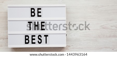 'Be the best' words on a modern board on a white wooden surface. Flat lay, overhead, top view. Space for text.