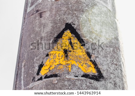a sign in the shape of a yellow triangle and lightning hangs on an ancient pillar; danger warning in vintage style