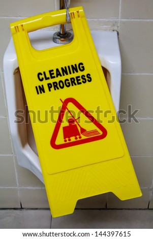 A Caution Sign warns people of a clean floor in  the men's restroom