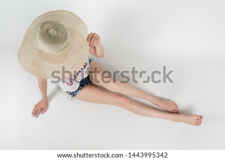the girl in shorts and hat covering her face sitting on white background isolated