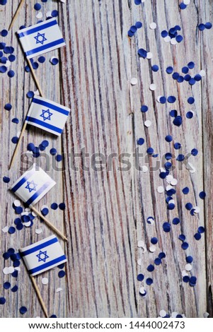 Israel independence day . April 29, 2020. white blue confetti paper with mini Israel flags on white wooden background , the concept of patriotism, strength and faith. copy space. vertical