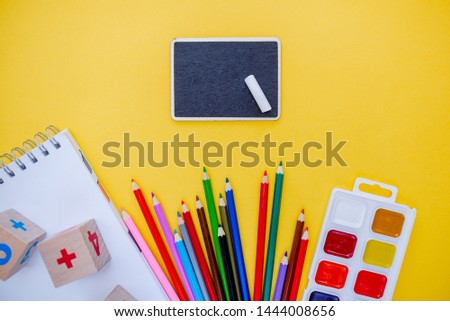 Back to school colorfull flatlay. Pencils notepad numbs a b c alphabet waterolors. Horizontal top view several objects above.