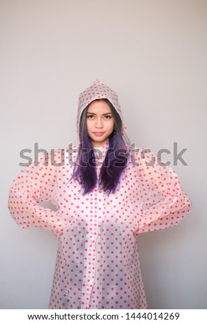 An attractive single Asian girl, shot body length, wearing a raincoat.