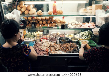 Vietnamese woman sell Vietnam bread on cart at night street food, stuffed food with meat, pork bologna, pickle, a famous and popular food that cheap, quick, Ho Chi Minh city Royalty-Free Stock Photo #1444020698