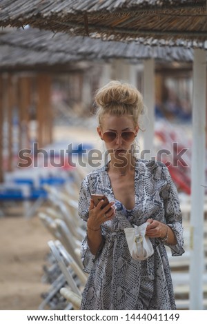 Young beautiful smiling woman wearing sunglasses in summer beach clothes over summer umbrellas 