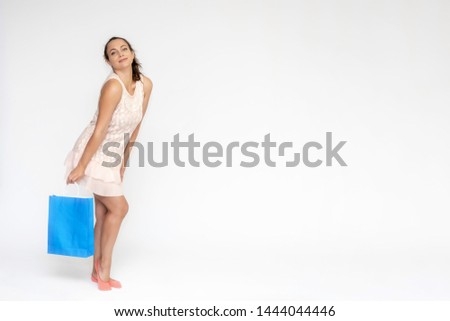 Full-length portrait on white background of a beautiful pretty woman girl in a pink dress, stands with purchases with packages in different poses with different emotions. Smiles Stylish trendy youth.