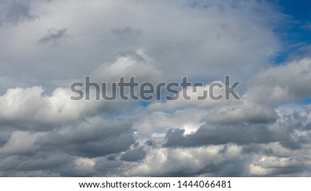 Blue sky with white and gray cumulus clouds.