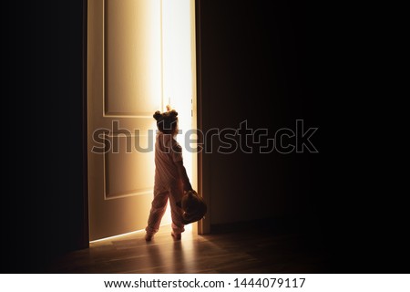 Little girl opens the door to the light in darkness