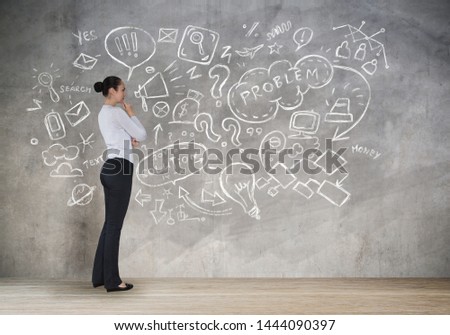 Young woman thinking over the business idea and looking at the sketch made of business and communication icons. Planning.
