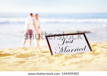 couple on the beach with plate with "just married" text on it