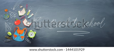 education and back to school concept. shapes cut from paper and painted of backpack, books, chemistry flask and apple over classroom blackboard with funny sketches. top view, flat lay