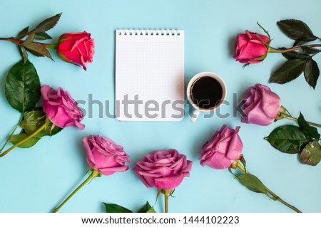 notepad cup of coffee and a bouquet of flowers on a blue background, business idea or concept