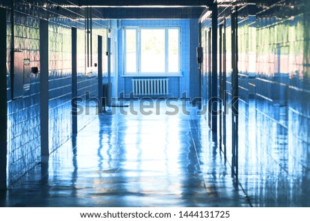 Blurry photo of hospital walk way with bright blue lighting. White floor with cool tone color with light tunnel in the middle of picture.
