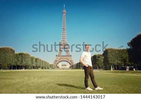 Young male tourist on field in front of Eiffel Tower Paris makes photo, France.