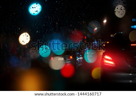 Taillight LED or rear light of modern car in the night street with raindrop and light bokeh. Traffic jam in the urban city with rainy night.