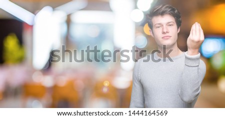 Young handsome man wearing winter sweater over isolated background Doing Italian gesture with hand and fingers confident expression