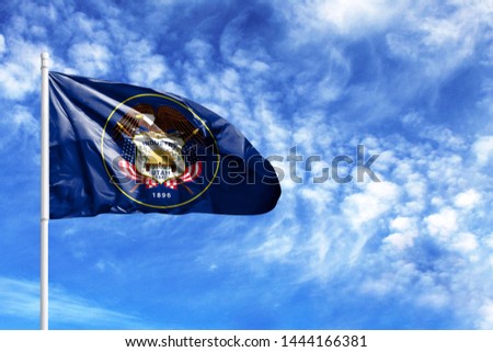 National flag State of Utah on a flagpole in front of blue sky