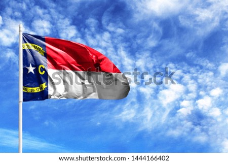 National flag State of North Carolina on a flagpole in front of blue sky