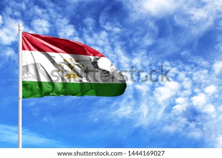National flag of Tajikistan on a flagpole in front of blue sky