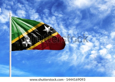 National flag of Saint Kitts and Nevis on a flagpole in front of blue sky