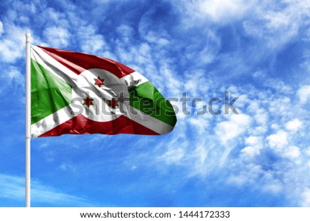 National flag of Burundi on a flagpole in front of blue sky