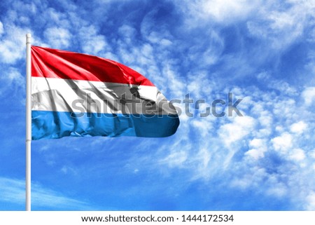 National flag of Luxembourg on a flagpole in front of blue sky