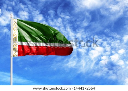 National flag of Chechen Republic on a flagpole in front of blue sky