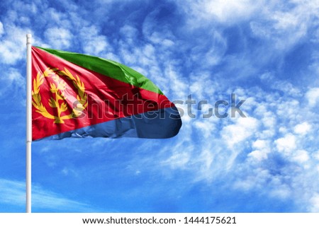 National flag of Eritrea on a flagpole in front of blue sky