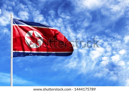 National flag of North Korea on a flagpole in front of blue sky