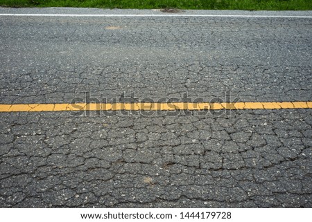 old Asphalt road cracked pattern with old traffic marking.
