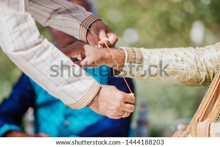 A brother is binding rakhi on hand of groom on wedding occasion