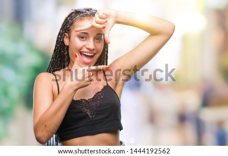 Young braided hair african american with pigmentation blemish birth mark over isolated background smiling making frame with hands and fingers with happy face. Creativity and photography concept.