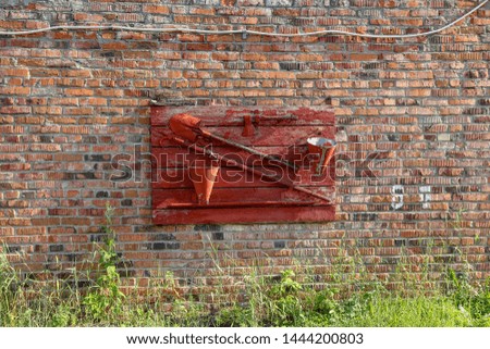Brick wall of the garage  with a red fire shield on summer day