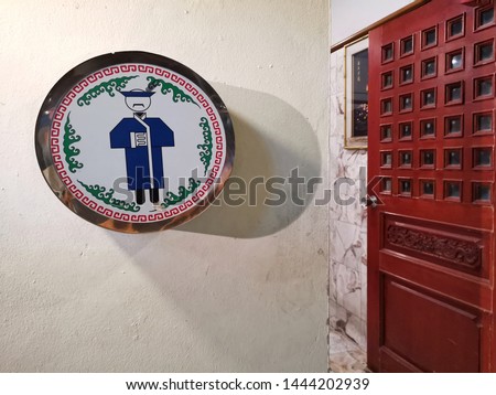 Man toilet sign in chinese style on​ white​ wall​ at​ Restaurant​ in​ Thailand.