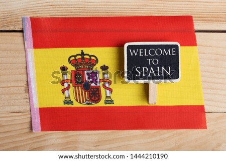 Greeting for traveler concept - Spain Flag and blackboard with text Welcome to Spain on wooden background