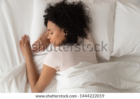Healthy serene young african american girl sleeping well in comfortable cozy fresh bed on soft pillow white linen orthopedic mattress, calm sleepy black woman enjoy peaceful sleep at home, top view Royalty-Free Stock Photo #1444222019
